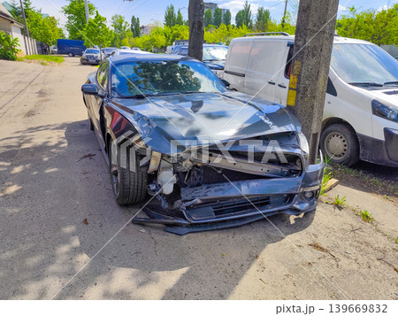 Smashed Front End of a Grey Sports Car After Collision With a Utility Pole on a City Street 139669832