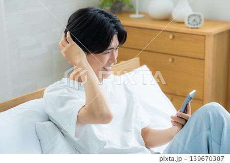 朝スマホを見て悩む男性 朝スマホを見て悩む男性 139670307