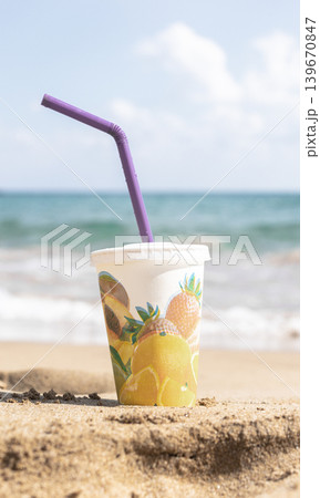 Drink cup with tropical fruit design on sandy beach near ocean Vintage style Drink cup with tropical fruit design on sandy beach near ocean Vintage style 139670847