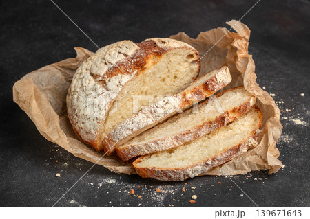 Sliced artisan sourdough bread on parchment paper over dark rustic background closeup for bakery advertising 139671643