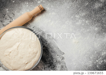 Fermented sourdough dough with rolling pin on flour covered rustic background for bakery advertising Fermented sourdough dough with rolling pin on flour covered rustic background for bakery advertising 139671655