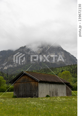 Rustic Barn in a Flowering Meadow Below Misty Alpine Mountain Rustic Barn in a Flowering Meadow Below Misty Alpine Mountain 139672130