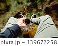 Man holding plastic cup of coffee in forest. Outdoor caffeine boost break with blurred nature background, energy and lifestyle concept 139672258