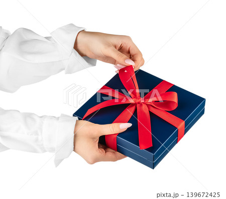 Gift box with red ribbon in female hands isolated background with copy space 139672425