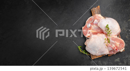 Raw chicken meat pieces on wooden board with herbs on dark background and copy space Raw chicken meat pieces on wooden board with herbs on dark background and copy space 139672541