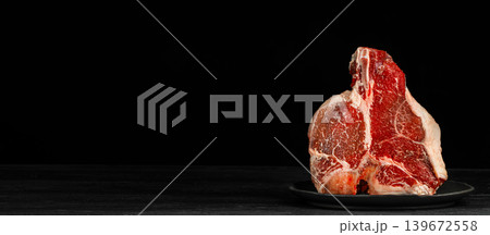Raw porterhouse t-bone steak on black background with dramatic lighting and copy space for premium food advertising Raw porterhouse t-bone steak on black background with dramatic lighting and copy space for premium food advertising 139672558