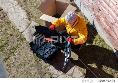 Modular compost system with stackable plastic parts being unpacked by rural resident near country home. Modular compost system with stackable plastic parts being unpacked by rural resident near country home. 139673214