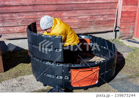 Assembling modular plastic composter factory produced from identical panels woman farmer pushes section through side grooves until locks in lower part snap shut. Assembling modular plastic composter factory produced from identical panels woman farmer pushes section through side grooves until locks in lower part snap shut. 139673244