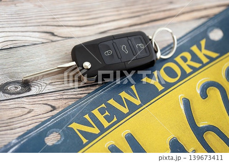 Remote control car keys on New York license plate on wooden background. Car driving in New York Remote control car keys on New York license plate on wooden background. Car driving in New York 139673411