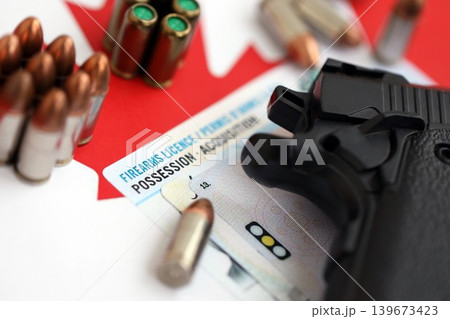 Canadian firearms license and handgun with bullets on Canadian flag close up. Gun permit concept Canadian firearms license and handgun with bullets on Canadian flag close up. Gun permit concept 139673423