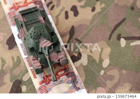 Russian rubles money bills and tank on camouflage fabric close up. Concept of russian army funds 139673464