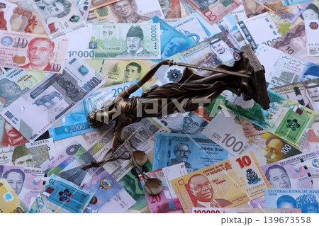 Themis figure against the background of pile of different currency money bills. Concept of justice Themis figure against the background of pile of different currency money bills. Concept of justice 139673558