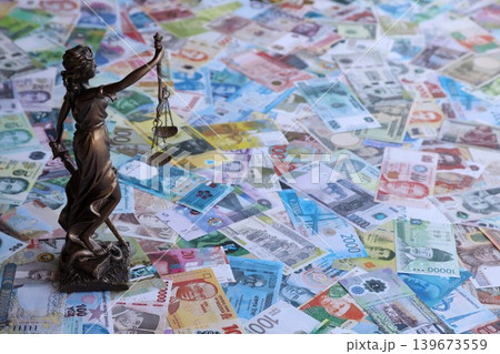 Themis figure against the background of pile of different currency money bills. Concept of justice Themis figure against the background of pile of different currency money bills. Concept of justice 139673559