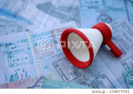 Megaphone on passport pages full of colorful stamp prints after travel and tourism Megaphone on passport pages full of colorful stamp prints after travel and tourism 139673591