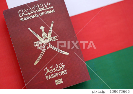 Omani passport on flag close up. Official identification document book for citizens of Oman Omani passport on flag close up. Official identification document book for citizens of Oman 139673666