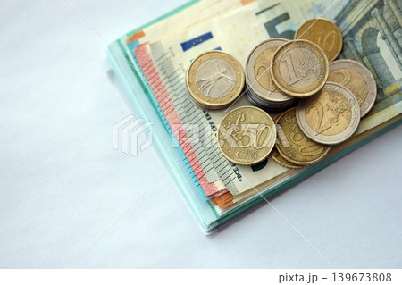 Eurozone euro money bills and cent coins pile on table. Eurozone coins on banknotes of EUR currency Eurozone euro money bills and cent coins pile on table. Eurozone coins on banknotes of EUR currency 139673808