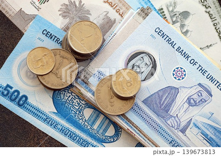 UAE dirham money bills and fils coins pile. United Arab Emirates coins on banknotes of AED currency 139673813