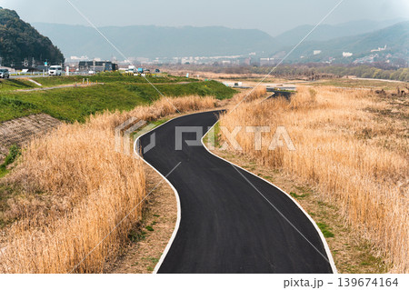 Freshly paved winding asphalt pathway through golden grassland in suburban Freshly paved winding asphalt pathway through golden grassland in suburban 139674164