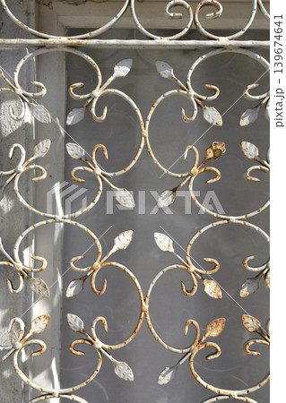 Ornate rusty wrought iron window grill with leaf motifs Ornate rusty wrought iron window grill with leaf motifs 139674641