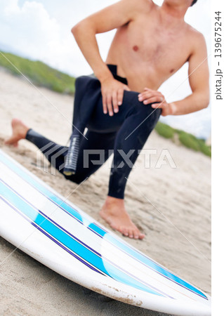 Surfer, man stretching legs and surfboard on beach, fitness and extreme sport, ready for waves with travel and sand. Summer, wet suit and warm up, start surfing and nature with adventure outdoor Surfer, man stretching legs and surfboard on beach, fitness and extreme sport, ready for waves with travel and sand. Summer, wet suit and warm up, start surfing and nature with adventure outdoor 139675244