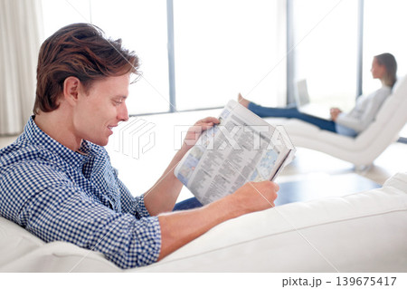 Man, newspaper and reading on sofa with relax for story, article or information with smile in living room. Person, news and morning routine on couch with print media or knowledge for break in lounge Man, newspaper and reading on sofa with relax for story, article or information with smile in living room. Person, news and morning routine on couch with print media or knowledge for break in lounge 139675417