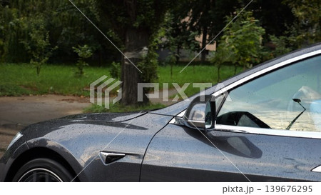 Businessman in shirt driving a modern electric car at sunny rainy day. Male successful entrepreneur riding on electrical vehicle at city. Young manager commuting to work at urban road. Slow motion Businessman in shirt driving a modern electric car at sunny rainy day. Male successful entrepreneur riding on electrical vehicle at city. Young manager commuting to work at urban road. Slow motion 139676295
