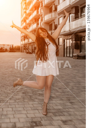 Woman happiness city girl in white dress jumping playfully on urban street during sunset expressing joy and freedom 139676964