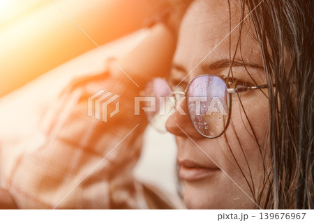 Woman glasses raindrops standing with wet hair and eyeglasses covered in moisture during a warm orange sunset glow Woman glasses raindrops standing with wet hair and eyeglasses covered in moisture during a warm orange sunset glow 139676967