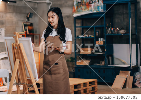 Female artist wears black hat posing near picture indoor the studio Female artist wears black hat posing near picture indoor the studio 139677305
