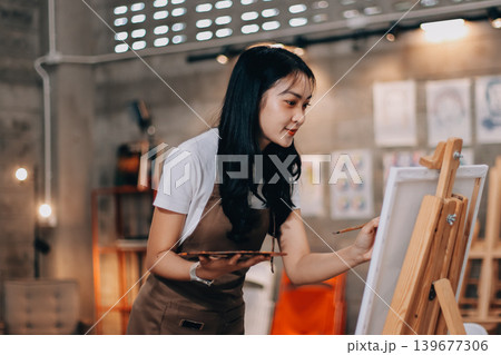 Female artist wears black hat posing near picture indoor the studio 139677306