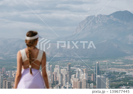 Woman in sportswear overlooking urban skyline and mountain landscape Woman in sportswear overlooking urban skyline and mountain landscape 139677445