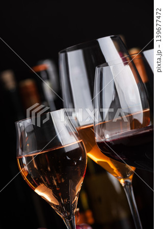 Close-up three glasses of red, white and sparkling rose wine with bunch of grapes on dark slate background Close-up three glasses of red, white and sparkling rose wine with bunch of grapes on dark slate background 139677472