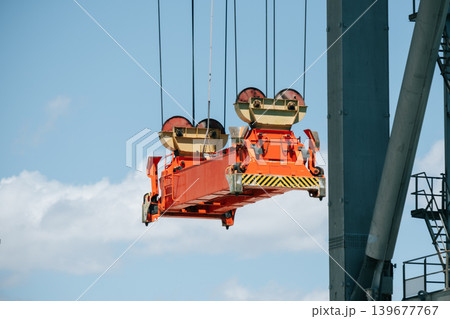 Industrial crane lifting bright red cargo in construction site Industrial crane lifting bright red cargo in construction site 139677767