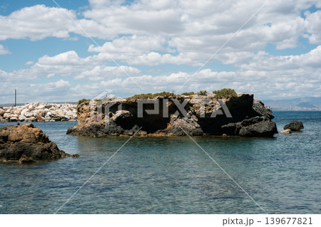 Coastal rock formations with clear blue water under a cloudy sky Coastal rock formations with clear blue water under a cloudy sky 139677821