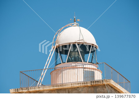 Coastal lighthouse against clear blue sky with dome and ladder 139677870