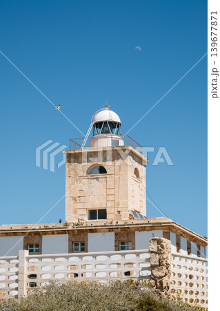 Historic lighthouse under clear blue sky with drone and moon in background 139677871