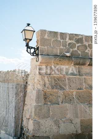 Historical stone wall with vintage lantern against clear sky Historical stone wall with vintage lantern against clear sky 139677890