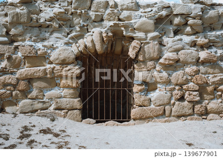 Ancient stone wall with iron gate in desert setting Ancient stone wall with iron gate in desert setting 139677901