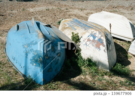 Abandoned boats resting on dry land with weathered paint and natural surroundings Abandoned boats resting on dry land with weathered paint and natural surroundings 139677906