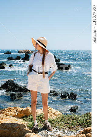 Young woman in sun hat enjoying coastal scenery on a sunny day Young woman in sun hat enjoying coastal scenery on a sunny day 139677957