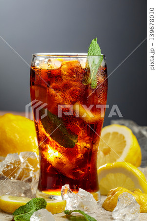 Cocktail Cuba Libre in a misted glass with lemon slices, ice and mint. Cocktail Cuba Libre in a misted glass with lemon slices, ice and mint. 139678010