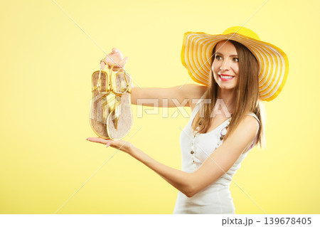 Woman in big yellow summer hat holds sandals Woman in big yellow summer hat holds sandals 139678405
