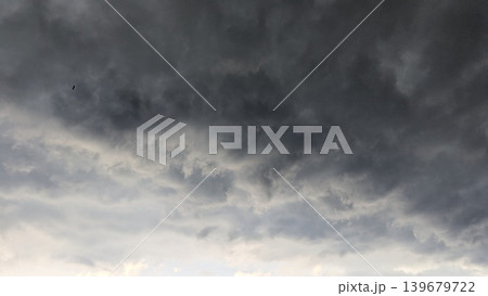 Dramatic, dark storm clouds fill the entire frame, creating a moody, atmospheric scene. Layers of heavy grey, charcoal vapor swirl across the sky, obscuring the sun. This natural texture represents 139679722