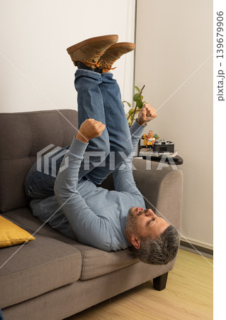 A man is laying on a couch and doing a handstand 139679906