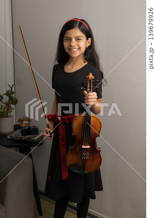 A young girl is holding a violin and smiling A young girl is holding a violin and smiling 139679926