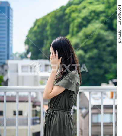 緑を背景に顔を覆う若い女性 緑を背景に顔を覆う若い女性 139680051