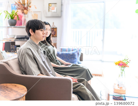ソファで並んで座る若いカップル ソファで並んで座る若いカップル 139680072