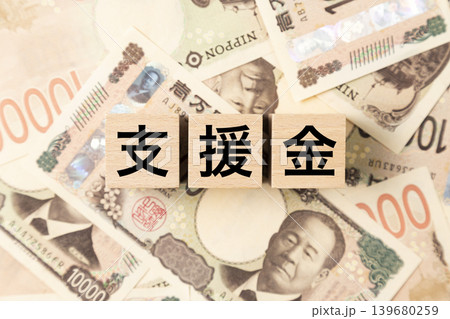 「支援金」と書かれたブロックとたくさんの一万円札 「支援金」と書かれたブロックとたくさんの一万円札 139680259
