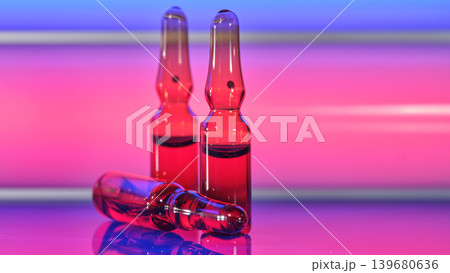 Red glass medical ampoules close up on neon pink blue background Red glass medical ampoules close up on neon pink blue background 139680636