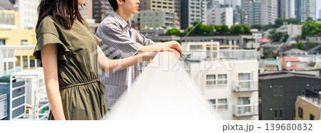 屋上の手すりに寄りかかる男女 139680832